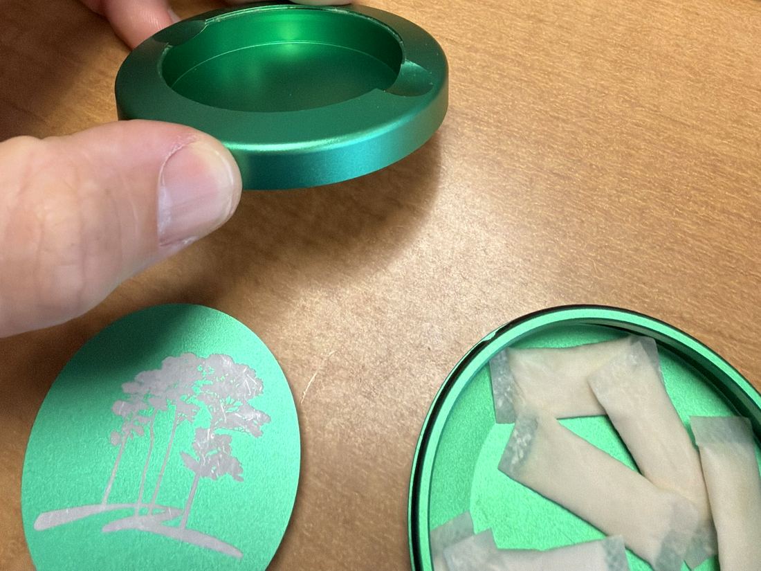 The tray held in one hand above the base, which is full of fresh pouches.
