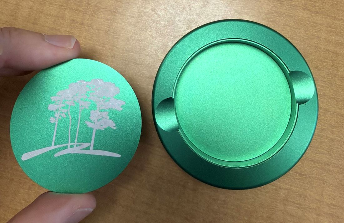 The engraved lid held next to the tin body, showing the recess it seats into.